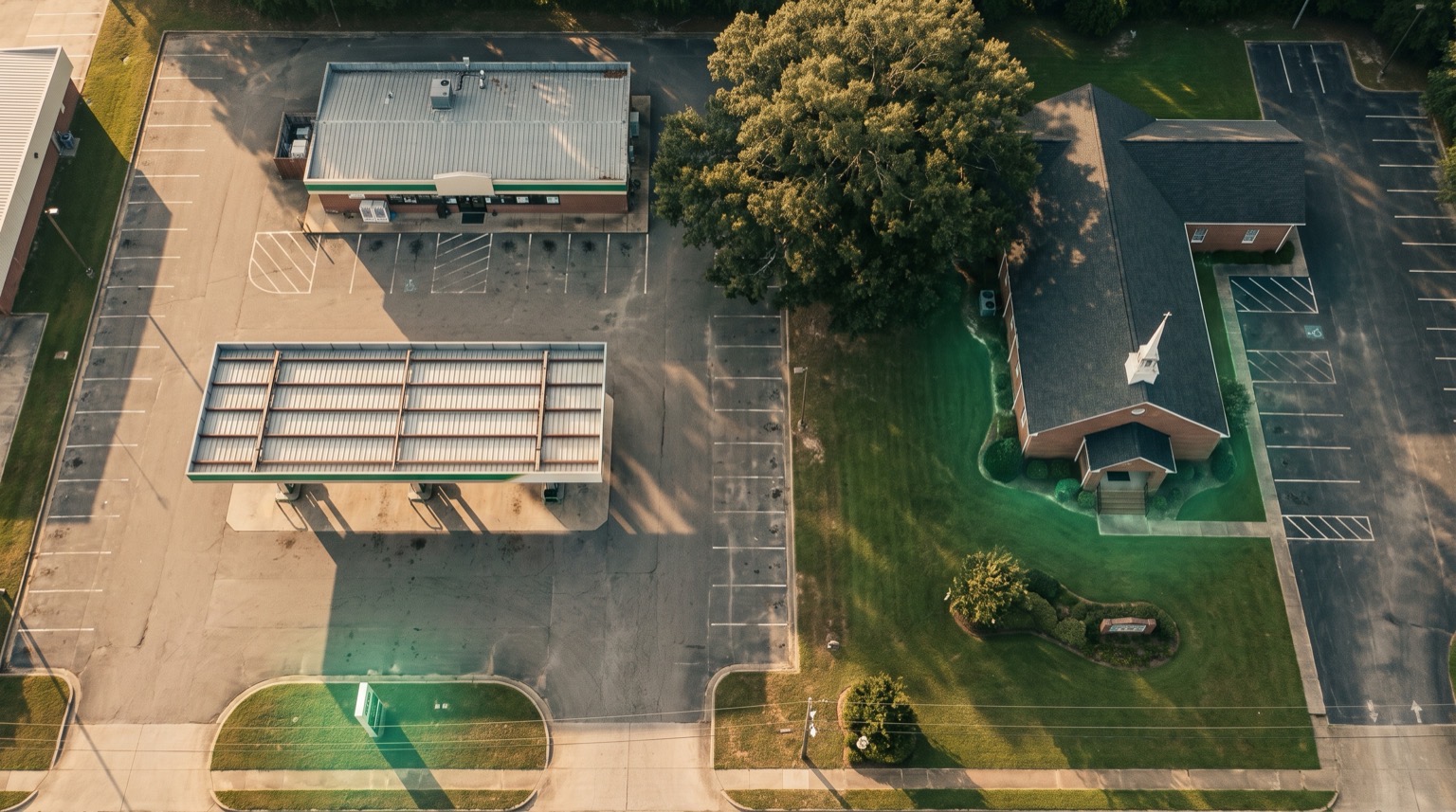 Warm, illustrative aerial view of a small commercial strip including a gas station and a church, framed like an overlooked property on a landscaper's map.